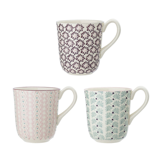 Three Maya stoneware mugs with white glaze and curved handles, patterned in purple floral, pink chevron, and green botanical motifs, shown on a plain white background.