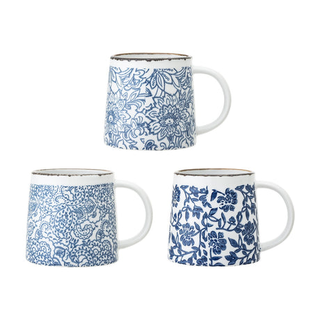 Set of 3 white stoneware mugs with blue floral patterns—outlined blooms, paisley leaves, and trailing stems—each featuring a white handle and dark rim.