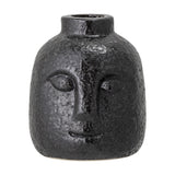 Eliot Stoneware Candle Holder in black, a small face-shaped taper holder with relief eyes, nose and smile, textured glossy finish, on a plain white background.