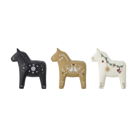 Set of three Siffer resin horse tealight holders in black, tan, and white, each painted with folk-art Christmas motifs like snowflakes, birds, and stars, shown on a plain white background.