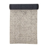 Saxo Cotton Rug 245x75cm runner, natural tone with geometric diamond pattern, shown half-rolled to reveal a dark woven underside, on a white background.