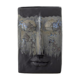 Nasru Stoneware Vase 22cm in black with a moulded face design, closed eyes, nose and lips, a speckled drip-glaze band across the eyes, set on a plain white background.