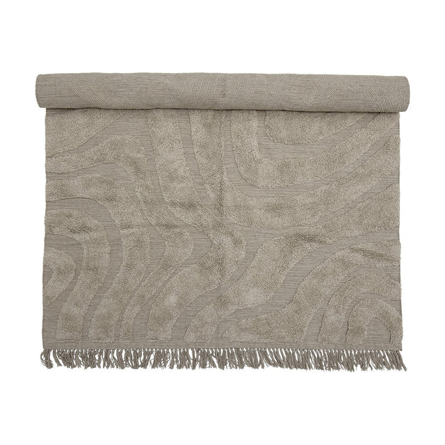 Elaine Wavy Cotton Rug 210x150cm in natural, partially rolled to show a tufted wavy pattern on flat-woven cotton with fringed edge, on a plain background.