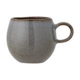 Sandrine Stoneware Cup in grey, round-bellied ceramic mug with speckled reactive glaze darkening towards the rim and a looped handle, shown on a plain white background.