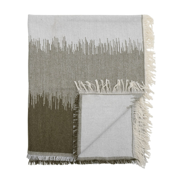 Lucienne Throw in Green, a folded woven acrylic-blend throw with a grass-like fade from deep green to light grey and knotted cream fringing, shown on a white background.