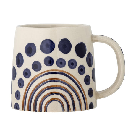 Shama Dotted Stoneware Mug 515ml in cream with hand-painted navy dot rings and a brown and blue arched rainbow motif, shown with its curved handle against a white background.