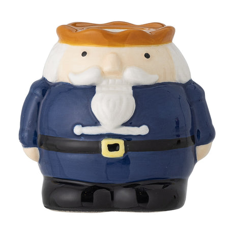 Stoneware nutcracker-shaped Christmas candle holder in navy coat with white beard, black belt and amber crown opening for a taper candle, on a white background.
