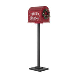 Red Carlo Christmas postbox decoration on black stand with curved slatted roof, Merry Christmas script, and pine cone wreath, shown on white background.