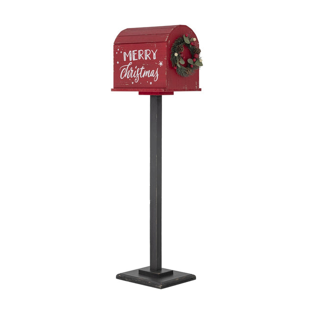 Red Carlo Christmas postbox decoration on black stand with curved slatted roof, Merry Christmas script, and pine cone wreath, shown on white background.
