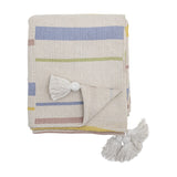 Pontino Striped Cotton Throw in cream, folded with blue, green, pink and yellow stripes and white corner tassels, shown on a plain white background.