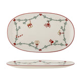Oval cream stoneware Christmas platter with red rim, featuring a pine garland, hearts, and ornament motifs like a drum, pig, candy cane, and pretzel, shown top and side views.
