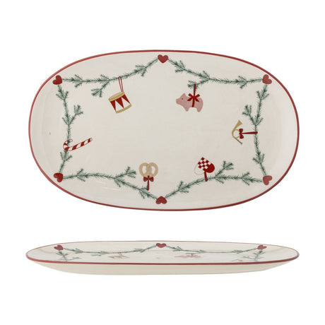 Oval cream stoneware Christmas platter with red rim, featuring a pine garland, hearts, and ornament motifs like a drum, pig, candy cane, and pretzel, shown top and side views.