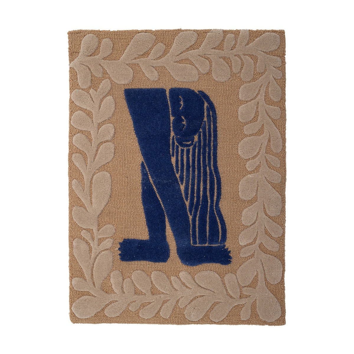 Atle Wool Wall Decor in Multi, a tufted wool hanging with a navy figure bent forward, hair falling in strands, framed by a tan leafy sprig border on a plain background.