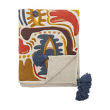 Horus Cotton Throw in Multi, folded cotton blend throw with bold abstract brushstroke pattern in red, blue, mustard and brown, finished with navy tassels, shown on a white background.
