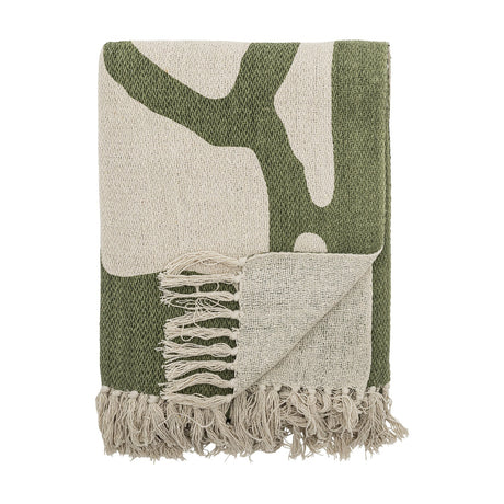 Dalmine Cotton Throw in green, folded with an abstract organic branch pattern on cream, finished with knotted fringe, shown on a white background.