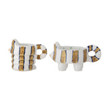 Set of 2 Caty striped stoneware cat candle holders in white and gold, with looped tail handles, one standing and one seated with a ribbed body, on a white background.