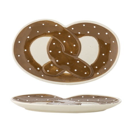 Stoneware serving platter shaped like a pretzel, glossy brown knot design with white salt-like dots on a cream base, shown from top and side views on a white background.