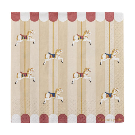 Square paper napkin from the Merry-go-round Christmas pack, printed with carousel horses on poles between striped bands and a red-and-white scalloped canopy edge, shown on a plain white background.