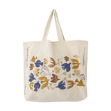 Beige woven cotton shopping tote with two handles, printed with a flock of stylised birds in blue, mustard, rust and cream, shown against a plain white background.