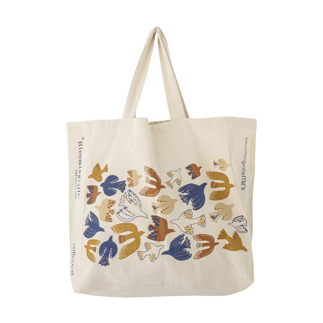 Beige woven cotton shopping tote with two handles, printed with a flock of stylised birds in blue, mustard, rust and cream, shown against a plain white background.