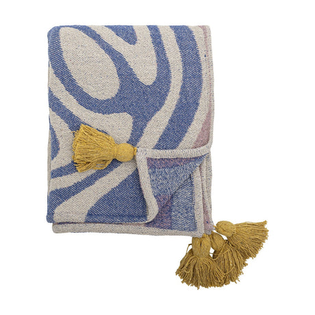 Arlie Throw in blue, folded woven fabric with a bold swirling stripe pattern and mustard-yellow tassels at the corners, shown against a plain white background.