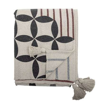 Forma Striped Throw in beige, folded to show a printed lattice of interlocking ovals on one side and fine stripes on the reverse, with tasselled corners against a plain white background.