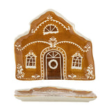 Brown stoneware Christmas platter shaped like a gingerbread house with pitched roof, wreath-hung door and three windows in hand-painted white detail, shown front and side.