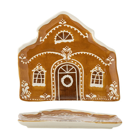 Brown stoneware Christmas platter shaped like a gingerbread house with pitched roof, wreath-hung door and three windows in hand-painted white detail, shown front and side.