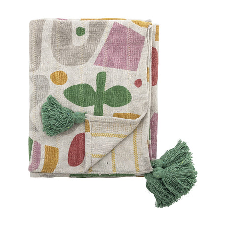 Filur Cotton Throw in Multi, folded showing an abstract shape print in pink, green, mustard and grey with green corner tassels, on a plain white background.
