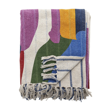 Artista Cotton Throw in Multi, folded to show abstract colour-block shapes in purple, green, blue and yellow with knotted fringe tassels, on a plain white background.