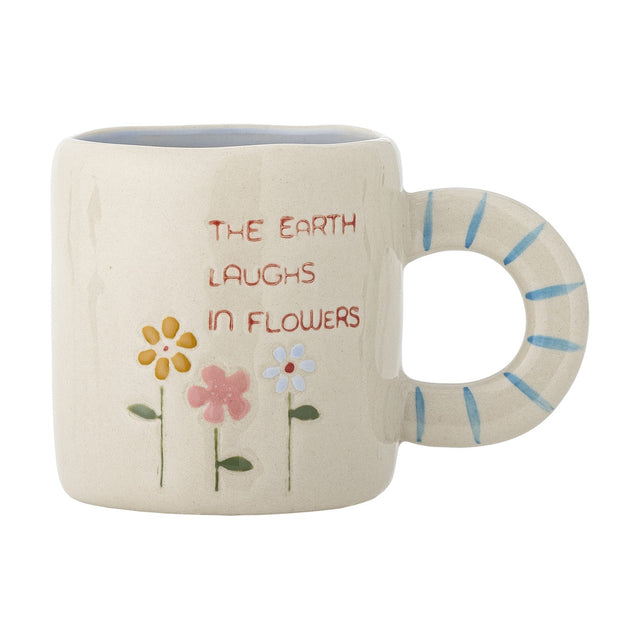 Cream stoneware cup with a round ring handle painted in blue stripes, featuring three hand-painted flowers and "The Earth Laughs in Flowers" text, set against a plain white background.