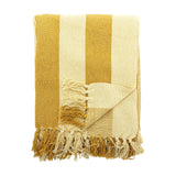 Frello Striped Cotton Throw in yellow, folded to show broad mustard and cream stripes with knotted fringe trim, set against a plain white background.