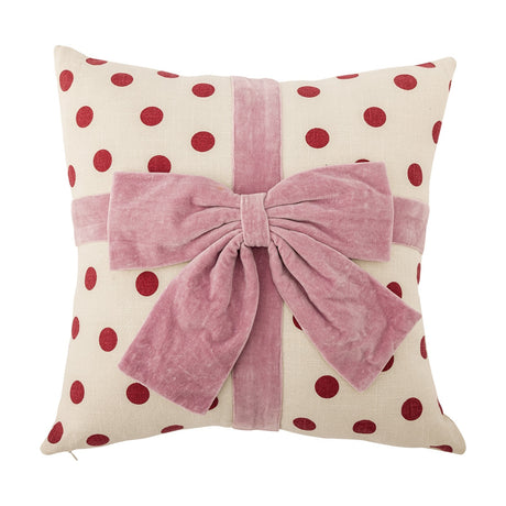 Bowie Dotted Cotton Christmas Cushion in cream with red polka dots, styled as a gift with a pink velvet ribbon and bow across the front, shown on a white background.