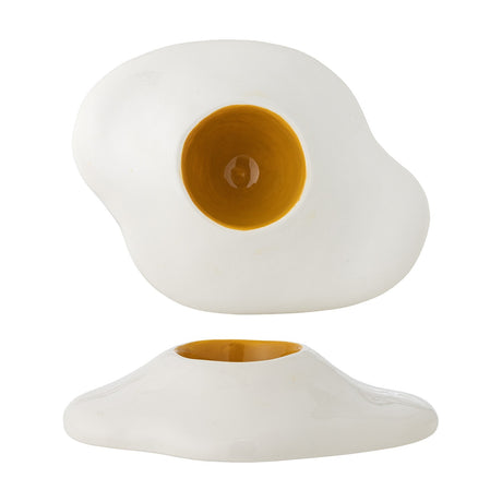 Eggert Stoneware Egg Cup in white, shaped like a fried egg with an irregular flat base and a round yellow-glazed well resembling the yolk, shown from above and in profile on a white background.