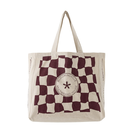 Beige cotton shopping tote with a wavy maroon check pattern and round "Bloomingville Multibrand House" badge at centre, shown on a plain white background.