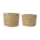 Indra Water Hyacinth Baskets, set of two oval woven storage baskets with ribbed texture from alternating plaited and twisted bands, natural finish, shown on a plain white background.