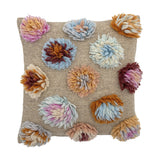 Somma Wool Cushion in Multi, a square woven cushion in beige with raised, shaggy multicoloured yarn tufts arranged across the front, shown on a plain white background.