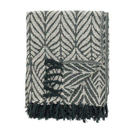 Ugento Leaf Cotton Throw in green, folded with a bold woven leaf pattern and knotted fringe edge, shown against a plain white background.