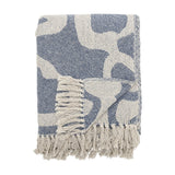 Salobre Cotton Throw in blue, folded showing an abstract flowing pattern in off-white with matching knotted fringe, shown on a plain white background.