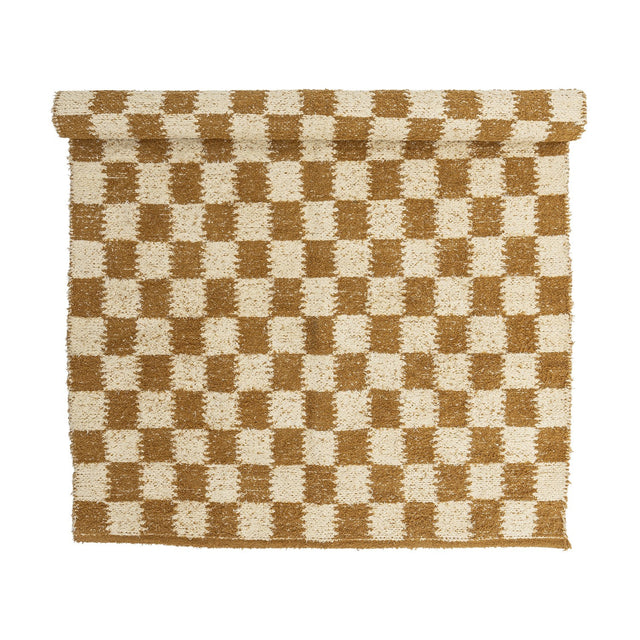 Chola Cotton Rug 200x140cm in Brown, a woven checkerboard pattern of brown and cream squares with softened edges and a textured, nubbly surface, partly rolled, shown on a plain white background.
