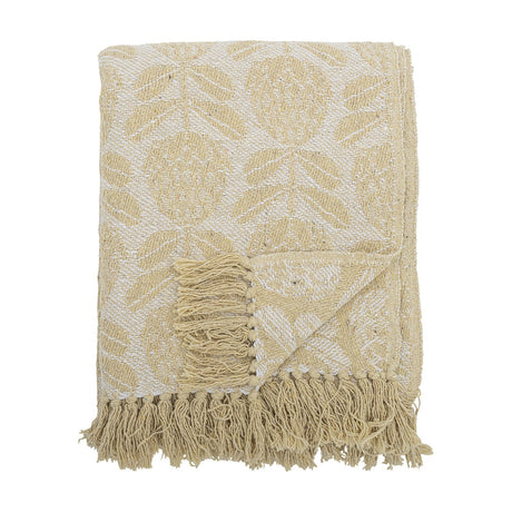 Pratello Throw in yellow, a woven fabric throw with a leafy floral pattern on a lighter ground, finished with fringed edges, folded on a plain white background.