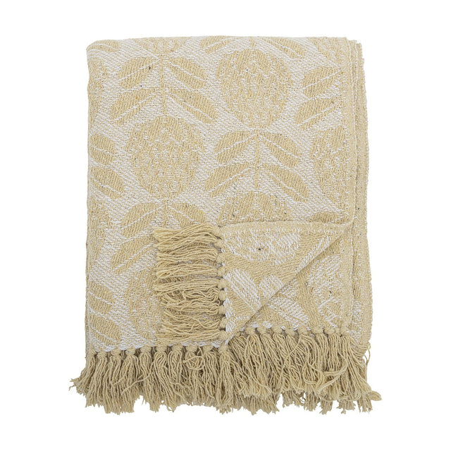 Pratello Throw in yellow, a woven fabric throw with a leafy floral pattern on a lighter ground, finished with fringed edges, folded on a plain white background.