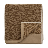 Kaysa Cotton Towel 100x50cm in brown, folded to show a coral-like woven pattern in light and dark brown tones with a plain woven border, on a white background.