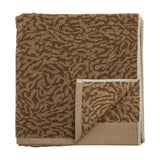 Kaysa Cotton Towel 140x70cm in brown, folded with a woven curling-branch pattern in light and dark tones and a plain beige border, shown on a white background.