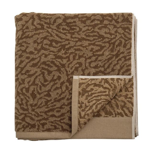 Kaysa Cotton Towel 140x70cm in brown, folded with a woven curling-branch pattern in light and dark tones and a plain beige border, shown on a white background.