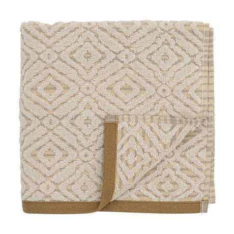 Malou Cotton Towel in Natural, folded hand towel with a woven geometric diamond pattern in cream and mustard, finished with a mustard-brown edge trim, on a white background.