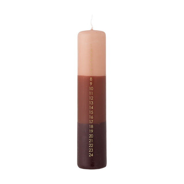 Tall slim pillar candle dip-dyed in pink, terracotta, and dark brown bands, featuring a gold 1–24 advent countdown printed down one side, shown on a white background.
