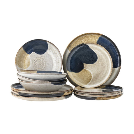 Jules Stoneware Dinner Set of 12 in multicoloured glaze, with large and small plates and deep bowls in beige and blue tones, stacked on a plain white background.