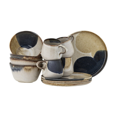 Jules Stoneware Breakfast Set of 12 in Multi, showing four cups, four bowls and four plates with a mottled reactive glaze in cream, beige and dark blue tones, arranged on a plain white background.