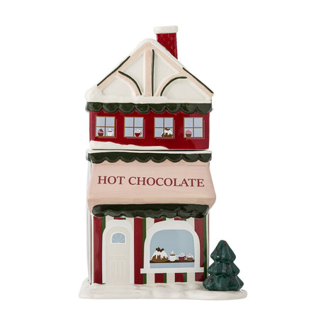 Gloria ceramic Christmas storage jar shaped as a red hot chocolate shop house with snow-topped roof, chimney, striped awning, and ceramic tree, 2500ml, on a white background.